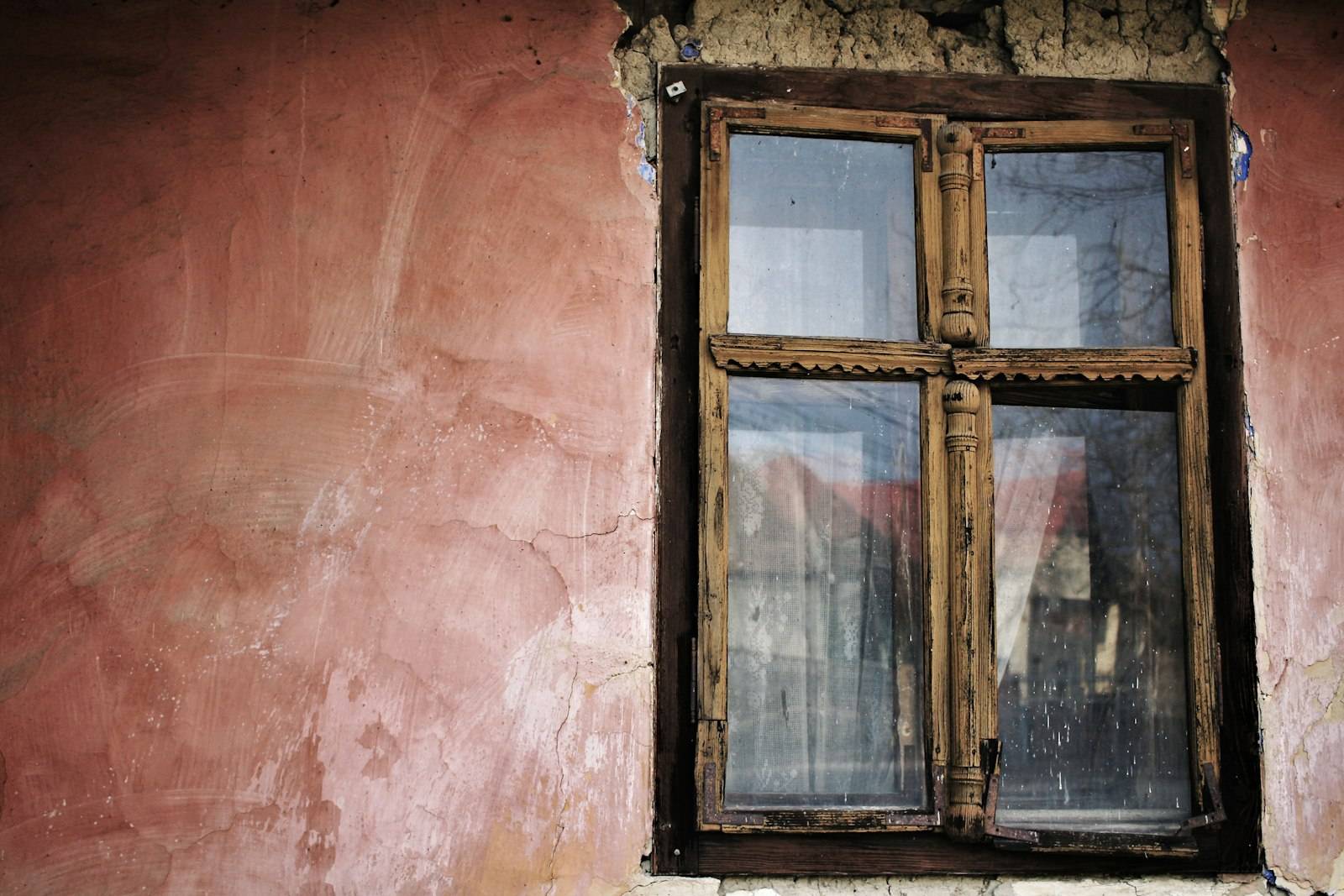 Fenêtre en bois à deux vantaux sur un mur ocre