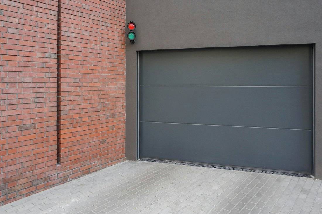 Porte de garage grise à panneau lisse sur une façade moderne
