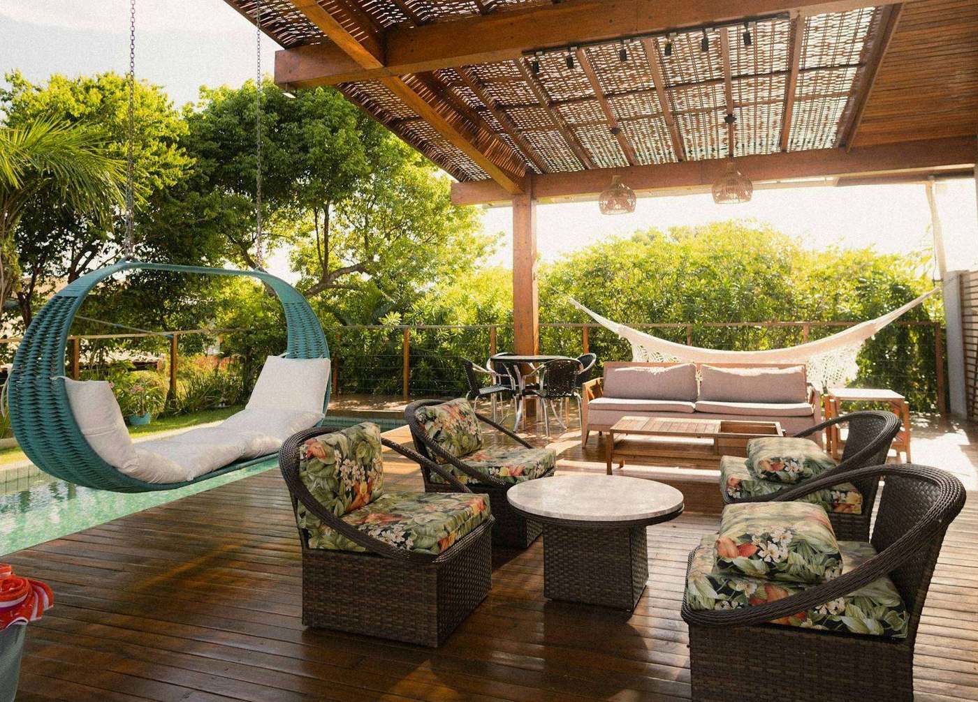 Terrasse en bois couverte d’une pergola, avec salon de jardin et hamac