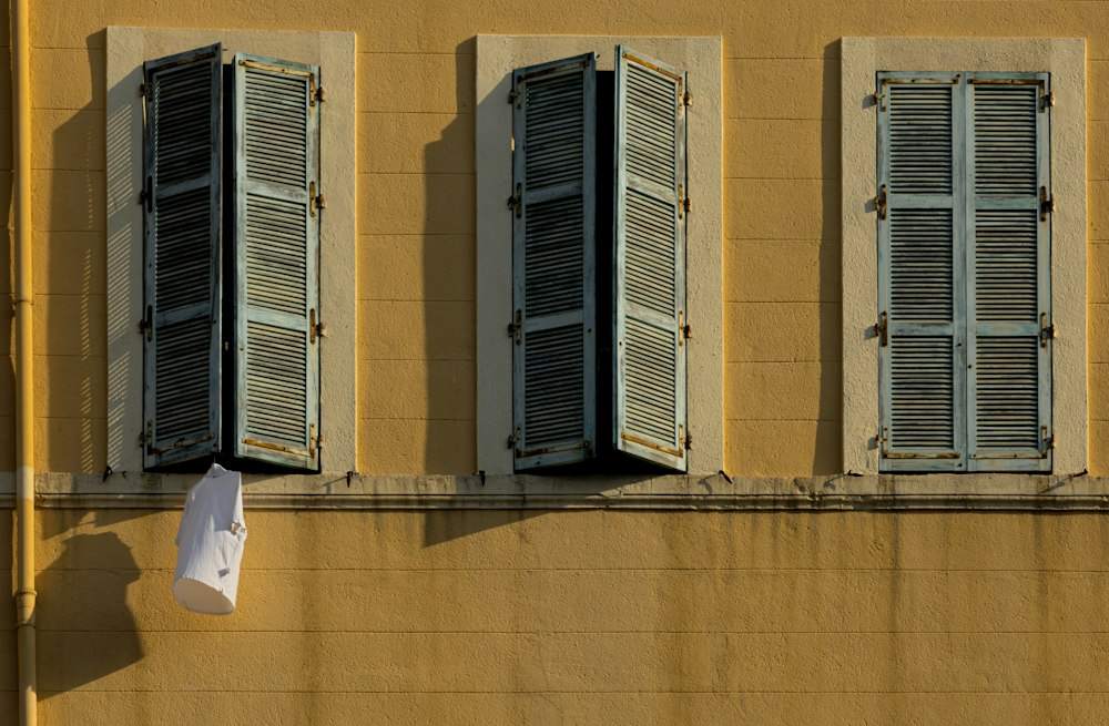 Persiennes entrouvertes sur une façade ocre