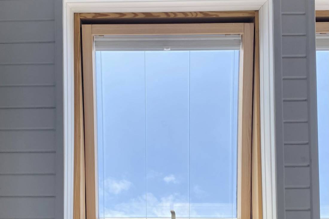 Fenêtre à cadre bois et vitrage clair sur une façade grise