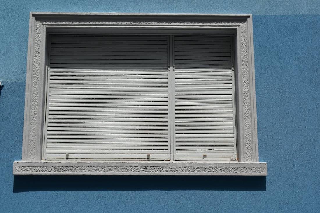 Volet roulant gris sur une façade bleue